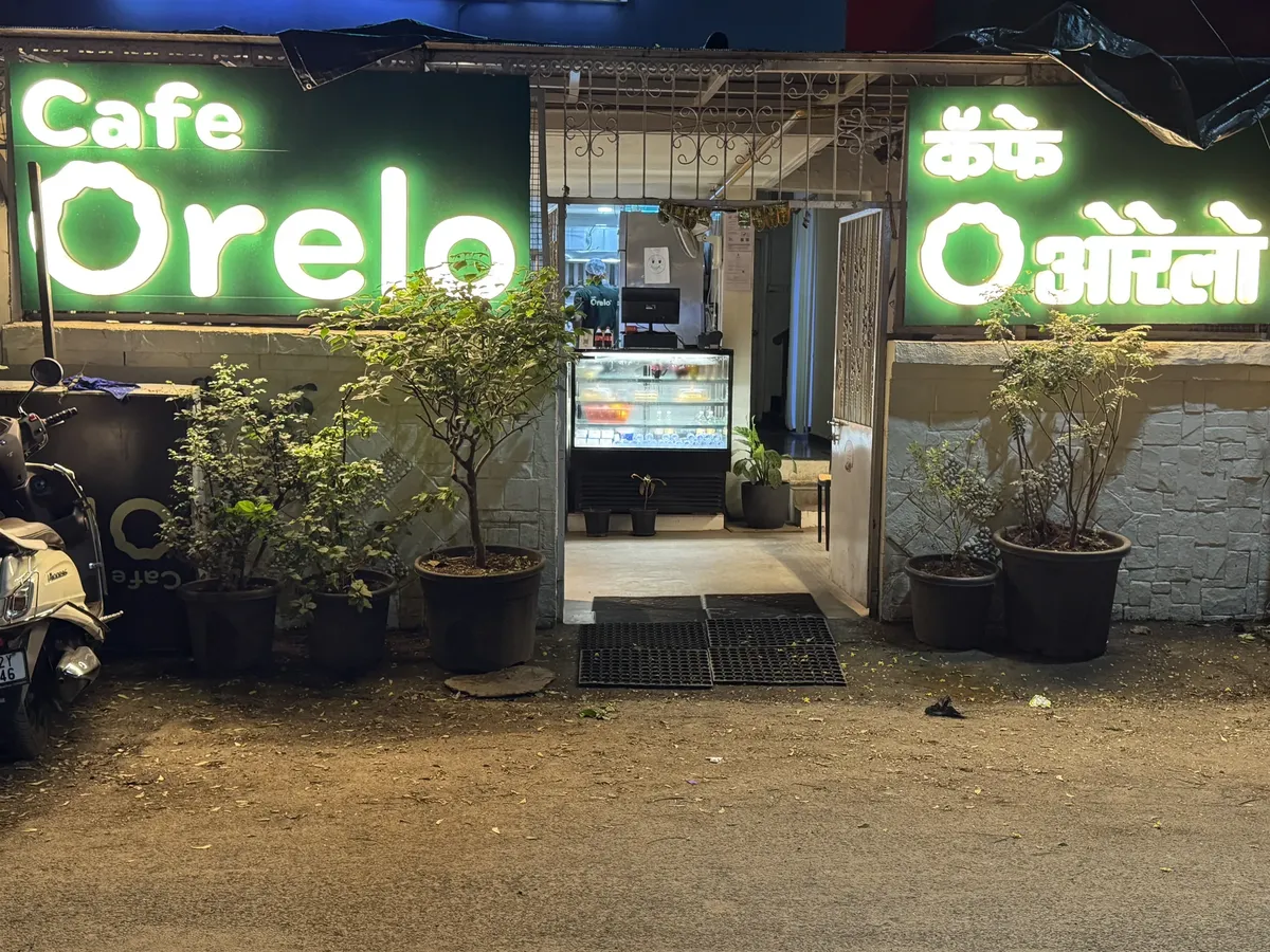 Cafe Orelo entrance with illuminated green signs in Wanowrie