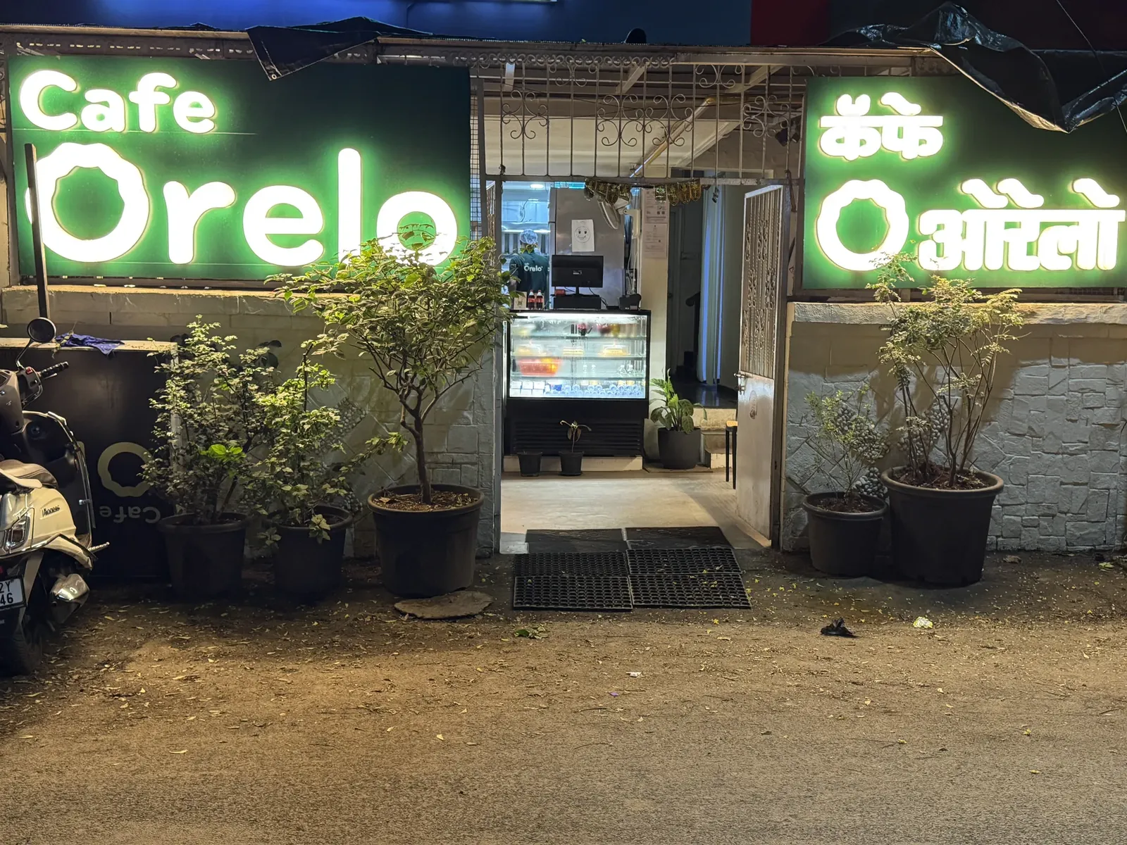 Cafe Orelo entrance with illuminated green signs in Wanowrie